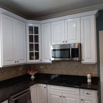 The image shows a kitchen with refinished, white cabinets and a microwave.