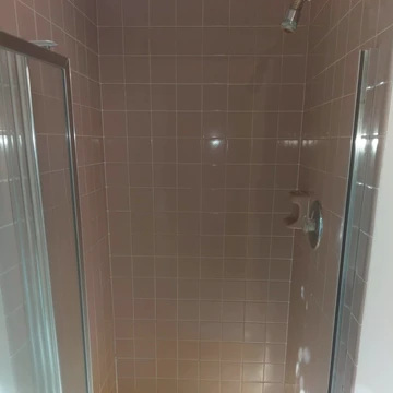 The image shows a shower with pink tile walls.